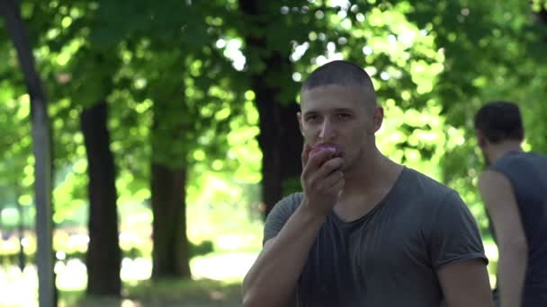 Hombre comiendo manzana en cancha de baloncesto — Vídeos de Stock