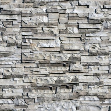 Duvardaki tuğlaların pürüzsüz dokusu vahşi taş arkaplan şeklinde. Gölgeli ve koyu renkli bej ve kahverengi tonlarda..