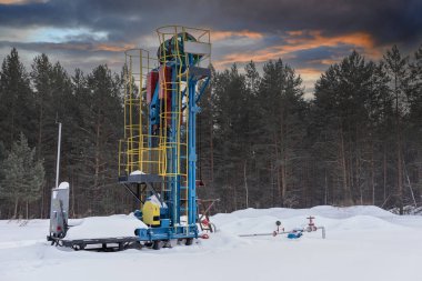 Petrol için petrol sondajı endüstriyel makinesi günbatımı arka planında tasarım için. Petrol pompası kışı çalışıyor. Güneş doğarken günbatımında gökyüzünün altında yağ pompası. 