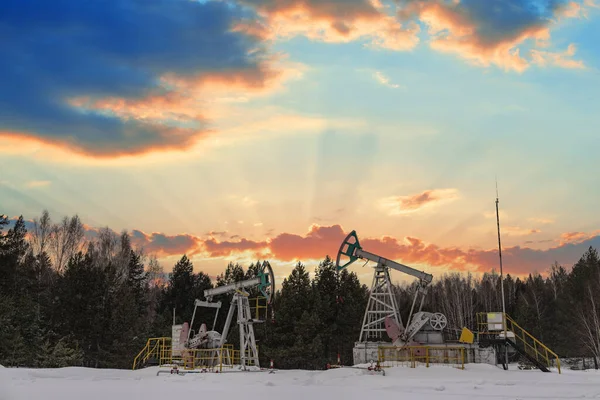 Oil pumps. Russia Oil industry equipment. Oil rig energy industrial machine for petroleum crude. Oil crisis. Fiery red clouds from the glow of the sun. Oil crisis. War on oil prices.