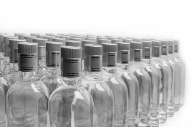 Etiketlenmemiş saf alkol şişeleri. Beyazın üzerinde izole edilmiş bir sürü alkollü içki şişesi. Damıtma üzerine kurulu küçük bir likör üretimi. Dolu şişeler arka arkaya yerleştirilir..  