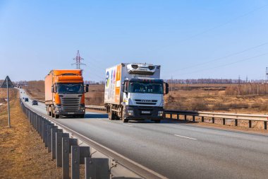 Tataristan, Rusya, Otoyol M7 - 14 Nisan 2021. IVECO kamyonu SCANIA kamyonunu geçiyor. Kamyonlar federal otoyol boyunca gidecekleri yere doğru hareket ediyor..