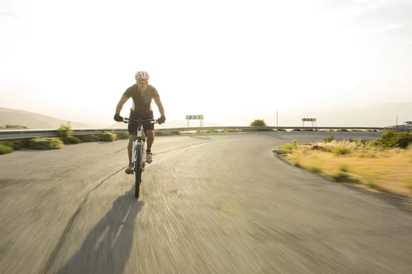 Ciclista homem montando bicicleta de montanha em dia ensolarado em uma estrada de montanha — Fotografia de Stock