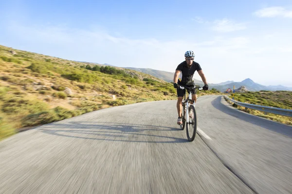 Radler fährt bei sonnigem Wetter Mountainbike auf einer Bergstraße — Stockfoto