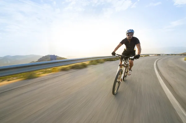 骑自行车的人男子骑山地自行车在晴朗的一天的山路上 — 图库照片