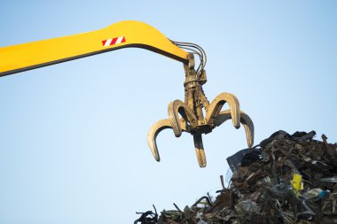 Large tracked excavator working a steel pile at a metal recycle  clipart