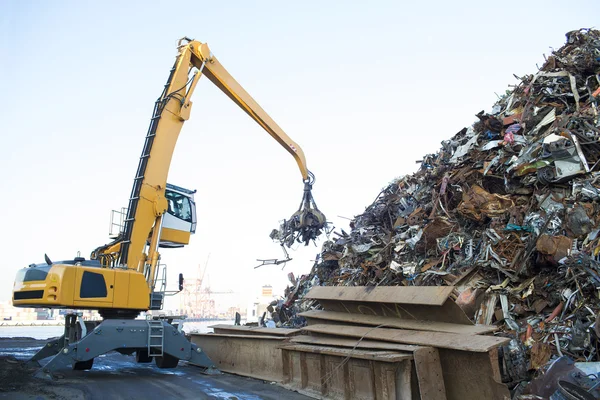 Grande escavadeira rastreada trabalhando uma pilha de aço em uma reciclagem de metal — Fotografia de Stock