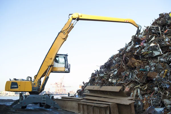 Grande escavadeira rastreada trabalhando uma pilha de aço em uma reciclagem de metal — Fotografia de Stock