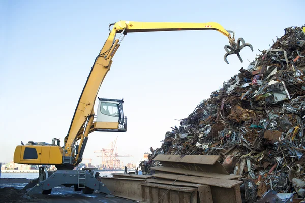 Excavadora de orugas grandes que trabaja una pila de acero en un reciclaje de metal —  Fotos de Stock