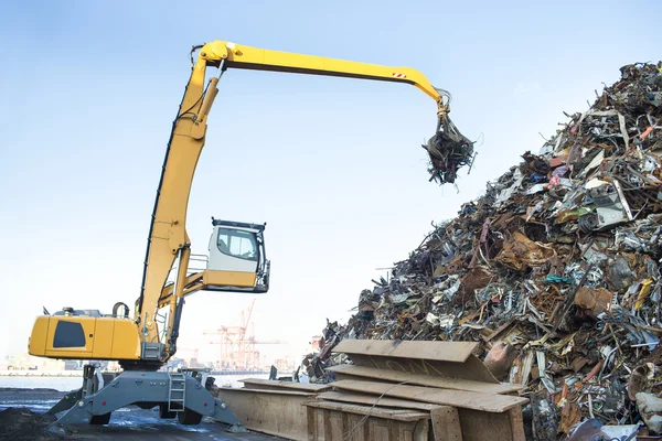 Excavadora de orugas grandes que trabaja una pila de acero en un reciclaje de metal —  Fotos de Stock