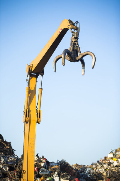 крановый коготь в верхней части кучи с металлоломом в центре переработки
