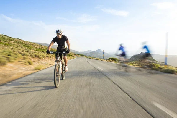 Kerékpáros ember lovaglás MTB napsütéses nap egy hegyi úton — Stock Fotó