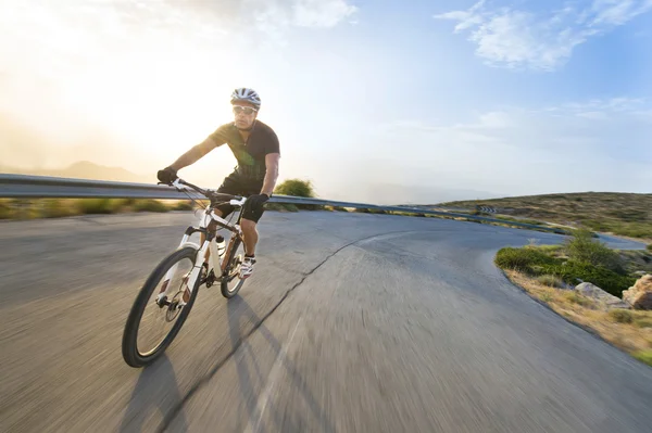 Fietser man paardrijden mountainbike in zonnige dag op een bergweg — Stockfoto