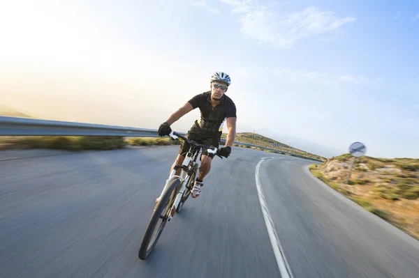 Rowerzysta człowiek jazda rower górski w słoneczny dzień na górskiej drodze — Zdjęcie stockowe