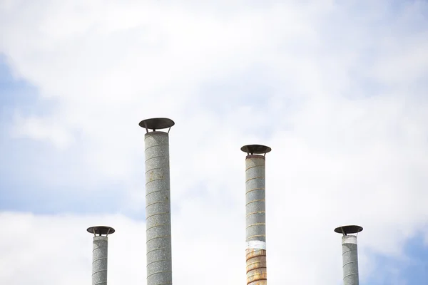 Quattro tubi di ventilazione sopra cielo blu primo piano — Foto Stock