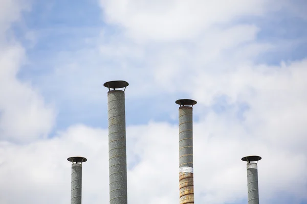 Quatro tubos de ventilação sobre o céu azul closeup — Fotografia de Stock