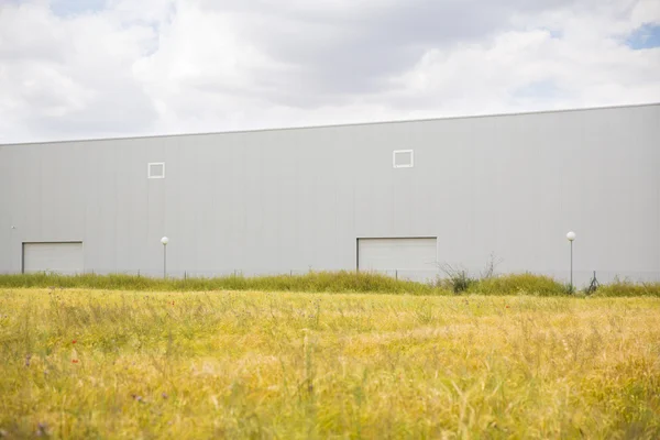 Edificio industrial cerca de campo y cielo azul — Foto de Stock