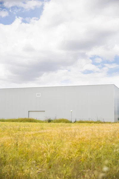 Edificio industriale vicino al campo e cielo blu — Foto Stock