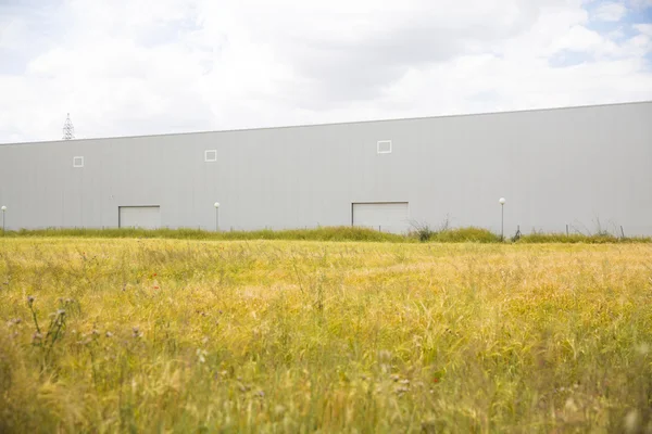 Industrial building near to field and blue sky — Stock Photo, Image