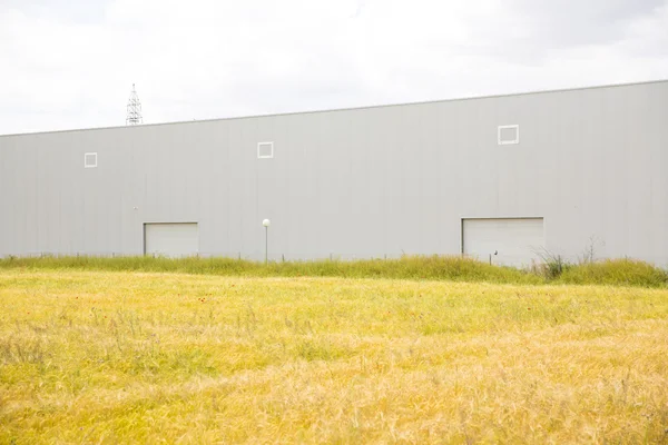 Edificio industrial cerca de campo y cielo azul — Foto de Stock