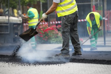 asfalt finişer makine yol yapımı sırasında işletim ve onarma işçi çalışıyor