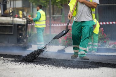 asfalt finişer makine yol yapımı sırasında işletim ve onarma işçi çalışıyor