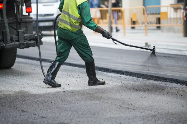 Werknemer die asfalt bestratingsafwerkmachines machine tijdens de aanleg van wegen en herstellen werkt — Stockfoto