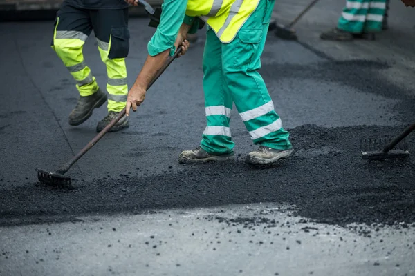 Werknemer die asfalt bestratingsafwerkmachines machine tijdens de aanleg van wegen en herstellen werkt — Stockfoto