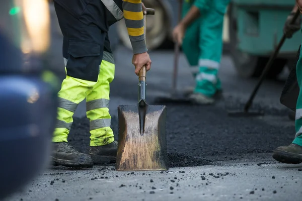 asfalt finişer makine yol yapımı sırasında işletim ve onarma işçi çalışıyor