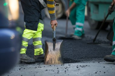 asfalt finişer makine yol yapımı sırasında işletim ve onarma işçi çalışıyor