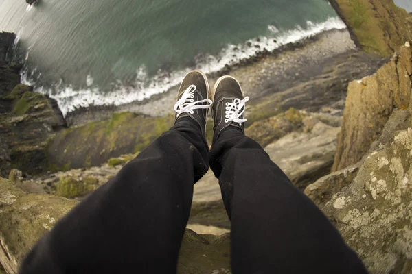 Legs hanging over a cliff