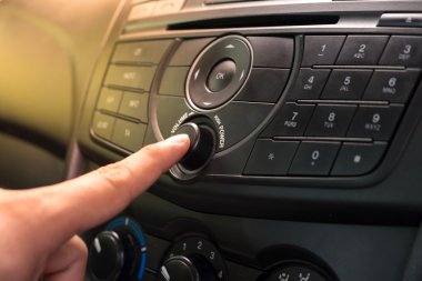 Hand Pushing the power button to turn on the car stereo system clipart