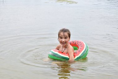 Çocuk lastik bir çemberle nehirde yüzüyor, mutlu çocuk.