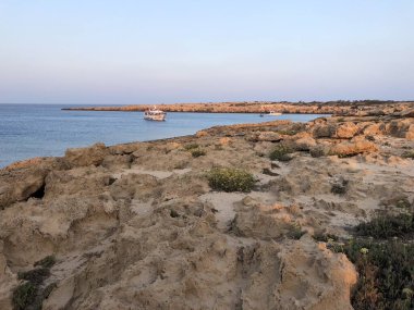 Kıbrıs, Greko Burnu, mavi gölün yanındaki kayalık dağlar. Denizdeki gemi