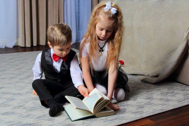 Erkek ve kız yerde oturmuş kitap okuyor.