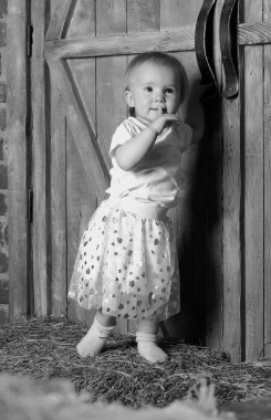 Küçük bir kız saklambaç oynuyor, büyük bir kapının arkasında saklanıyor.