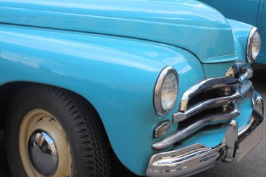 40 'lı yılların arabasının ön tarafı mavi, yuvarlak farlı ve krom ızgaralı.