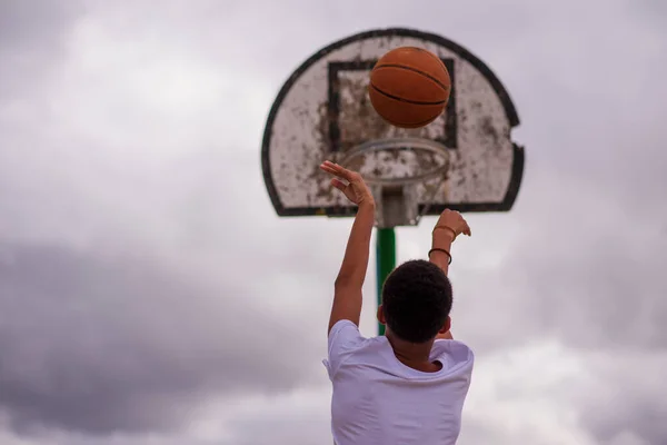 Rückansicht eines kleinen Jungen, der Basketball in Richtung Korb schießt — Stockfoto