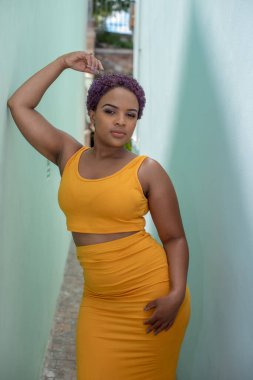 Duvara yaslanmış kendinden emin genç bir kadın.