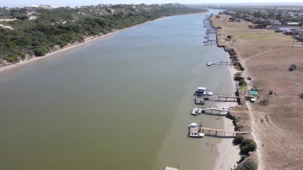 Aerial view of drone flying over river with boats docked — Stock Video