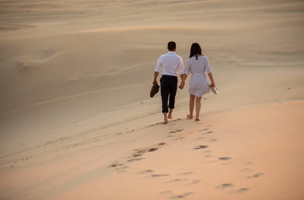 Pareja caminando en la duna de arena mientras se toma de la mano — Foto de Stock