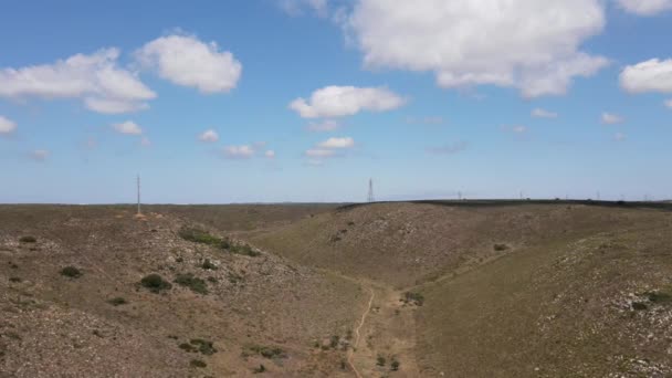 Drone vliegen over het veld met wolken zweven boven en elektrische pylonen gezien op de achtergrond — Stockvideo