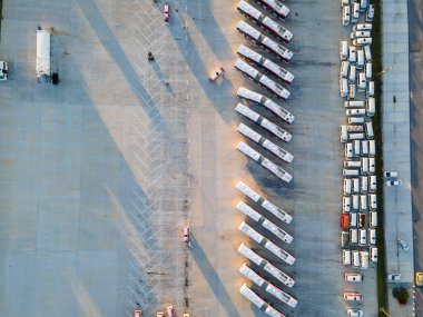 Asfalt üzerinde park edilmiş otobüsler yüksek açılı görüntüden görülüyor