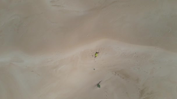 Widok z powietrza kobiety leżącej na wydmie z dronem lecącym w jej kierunku — Wideo stockowe