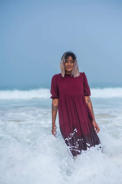 Porträt einer schönen Frau, die im Wasser steht, mit Wellen im Hintergrund — Stockfoto