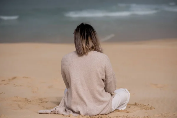 Vista trasera de la mujer sentada sola en la playa — Foto de Stock