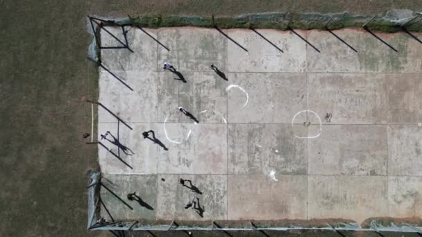 Вид с воздуха на группу детей, играющих в футбол на бетонной плите — стоковое видео