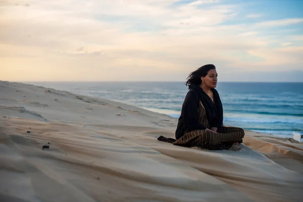 Frau sitzt auf Sanddüne am Strand — Stockfoto