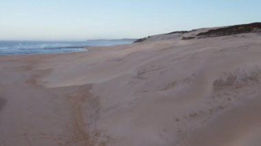 Kum tepelerinin üzerinden sahile doğru uçan insansız hava aracı görüntüsü