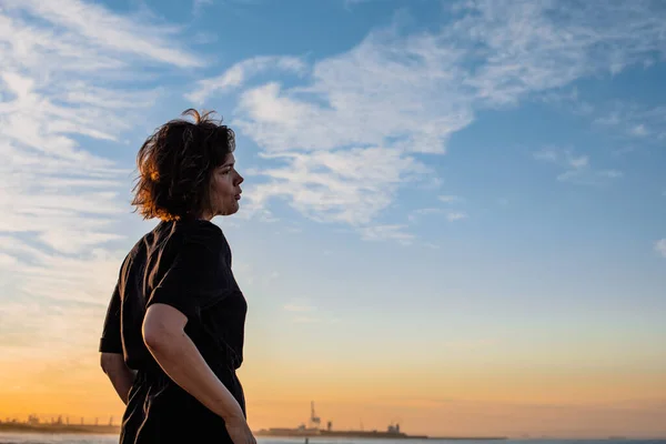 Nahaufnahme einer Frau, die bei Sonnenuntergang auf das Meer starrt — Stockfoto